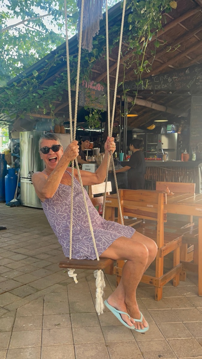 Kelley, host of Cozumel vacation rentals, laughing on a swing at a local restaurant